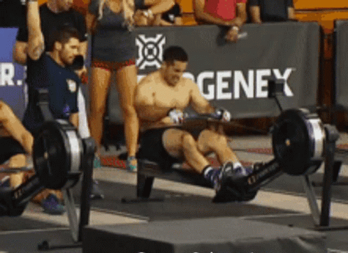 A Man Is Using A Rowing Machine In Front Of A Genex Sign GIF