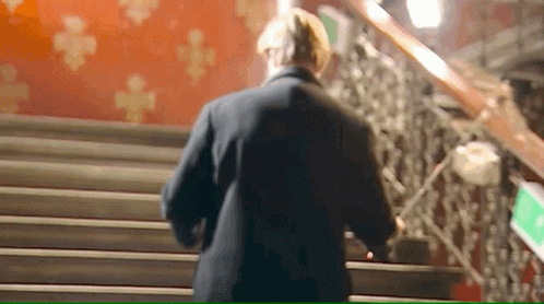 A Man Is Walking Down A Set Of Stairs . GIF