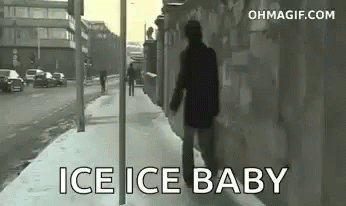 A Man Is Walking Down A Snowy Sidewalk With The Words `` Ice Ice Baby '' Written On The Sidewalk . GIF