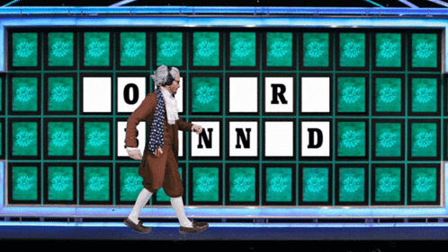 A Man Is Walking In Front Of A Wheel Of Fortune With The Letters O R N And D GIF