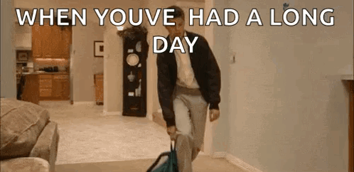 A Man Is Walking Through A Living Room Carrying A Suitcase And A Backpack . GIF