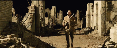 Man Walking Through Ruined City With Gun GIF