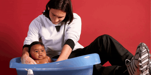 a man is washing a baby in a blue bathtub