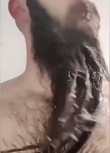 A Man Is Washing His Hair In A Bathtub With Water Coming Out Of His Head . GIF