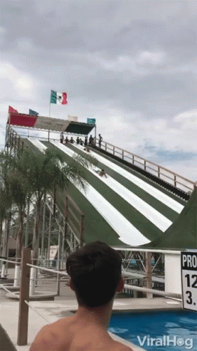 A Man Is Watching A Person Slide Down A Water Slide At A Water Park With The Words Viralhog On The Bottom GIF
