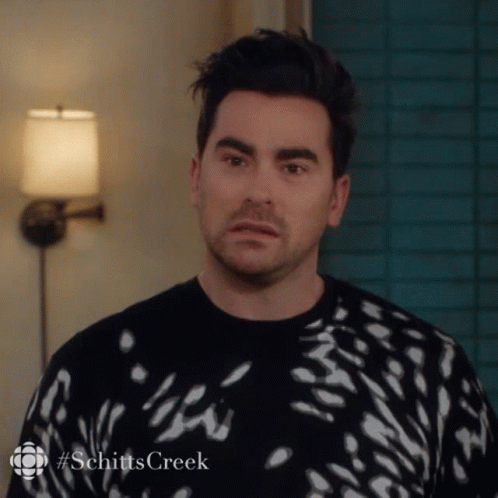 A Man Is Wearing A Black And White Sweater With The Word Schitts Creek On The Bottom GIF