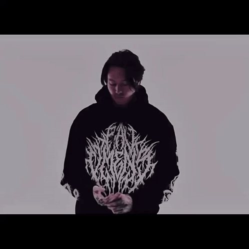 A Man Is Wearing A Black Hoodie With A White Logo On The Front GIF