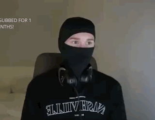 a man is wearing a black mask and headphones while sitting in a chair .