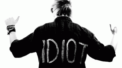 A Man Is Wearing A Black Shirt With The Word Idiot Written On It . GIF