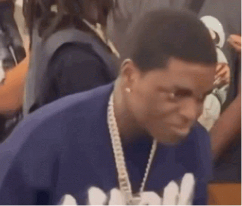 A Man Is Wearing A Blue Shirt And A Chain Around His Neck . GIF