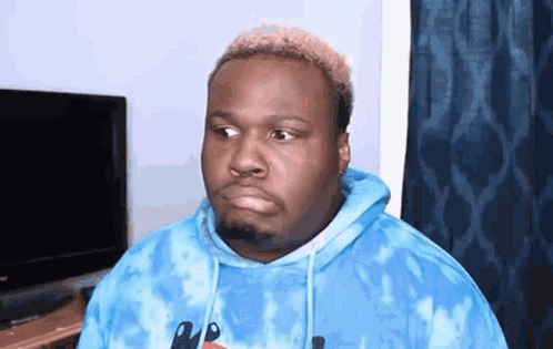 A Man Is Wearing A Blue Tie Dye Hoodie And Making A Funny Face . GIF