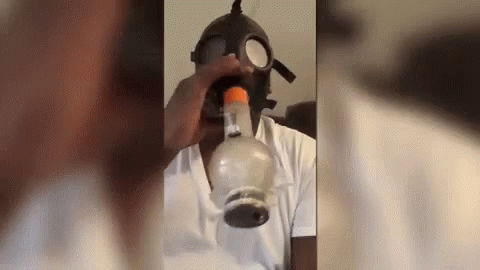 A Man Is Wearing A Gas Mask And Smoking A Bong . GIF