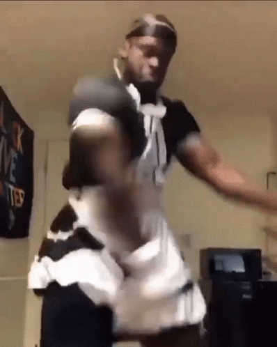 a man is wearing a maid costume and dancing in a room .