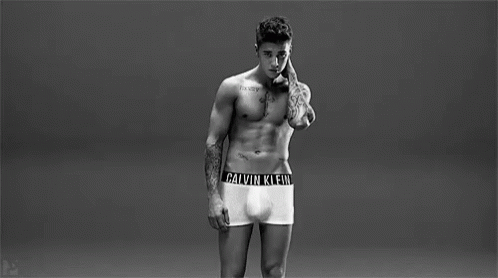 A Man Is Wearing A Pair Of Calvin Klein Underwear With A Black Band Around His Waist . GIF