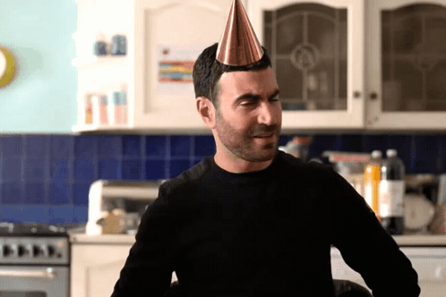 A Man Is Wearing A Party Hat And Making A Funny Face GIF