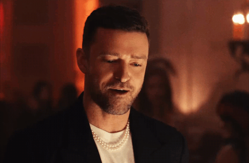 A Man Is Wearing A Pearl Necklace And A Black Jacket GIF