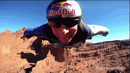 A Man Is Wearing A Red Bull Helmet And Sunglasses GIF