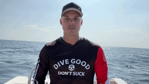 a man is wearing a shirt that says dive good don 't suck