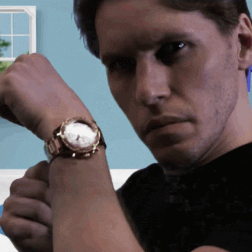 A Man Is Wearing A Watch On His Wrist And Looking At The Camera GIF