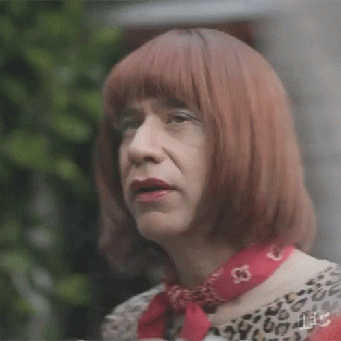 A Man Is Wearing A Wig And A Red Scarf . GIF