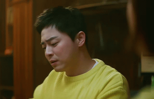 A Man Is Wearing A Yellow Sweater And Making A Funny Face GIF