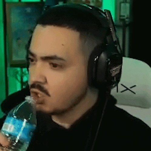 A Man Is Wearing Headphones And Drinking Water From A Bottle . GIF