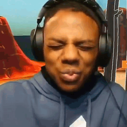 A Man Is Wearing Headphones And Making A Funny Face . GIF