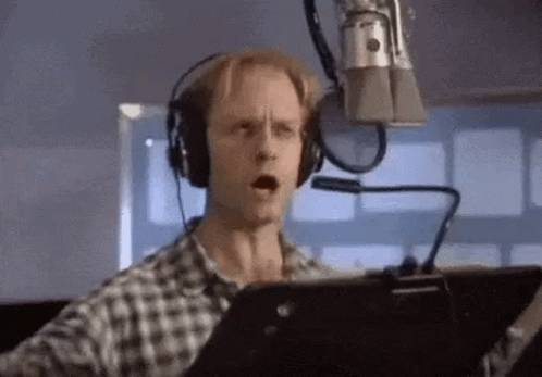 a man is wearing headphones and singing into a microphone .