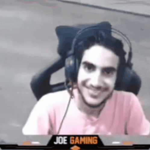 A Man Is Wearing Headphones And Smiling While Sitting In A Chair . GIF