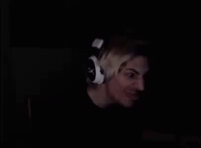 A Man Is Wearing Headphones In The Dark And Smiling . GIF