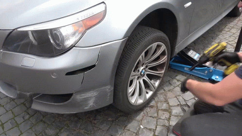 A Man Is Working On A Bmw With A Drill GIF