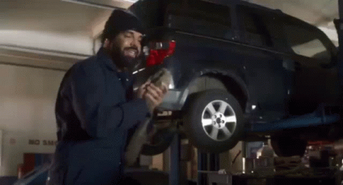 A Man Is Working On A Car In A Garage With A No Smog Sign In The Background GIF