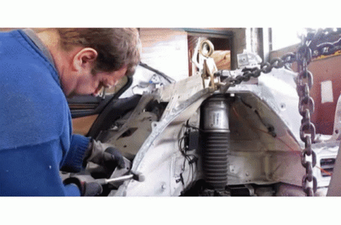 A Man Is Working On A Car With A Shock Absorber Attached To It GIF