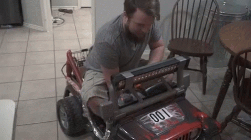 A Man Is Working On A Toy Jeep That Has The Number 001 On The Front GIF