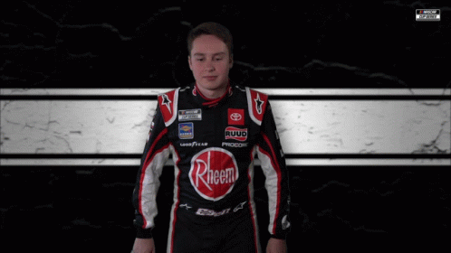 A Man Is Wrapped In A Black And White Checkered Blanket With A Nascar Logo In The Corner GIF