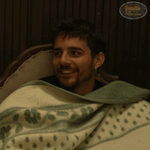 A Man Is Wrapped In A Green And White Blanket With The Word Paradiso On The Bottom Right GIF