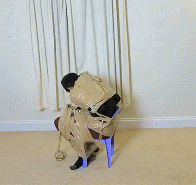 A Man Is Wrapped In Duct Tape And Sitting On A Blue Chair GIF