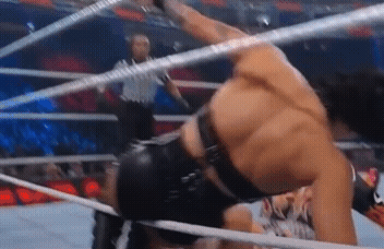 A Man Is Wrestling In A Ring While A Referee Watches . GIF