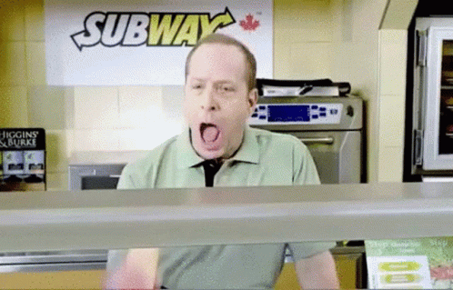A Man Is Yawning In Front Of A Sign That Says Subway GIF