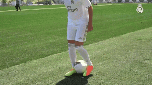 a man kicking a soccer ball on a field that has adidas signs
