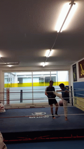 A Man Kicking Another Man In A Boxing Ring With A Sign That Says Show On It GIF