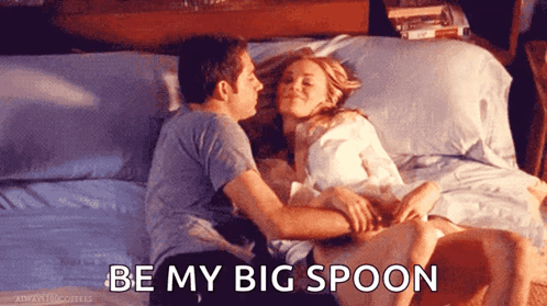 A Man Kissing A Woman On The Forehead While Laying On A Bed With The Words " Be My Big Spoon " Below Them GIF