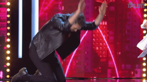 A Man Kneeling Down On A Stage With The Word Talent On The Screen GIF