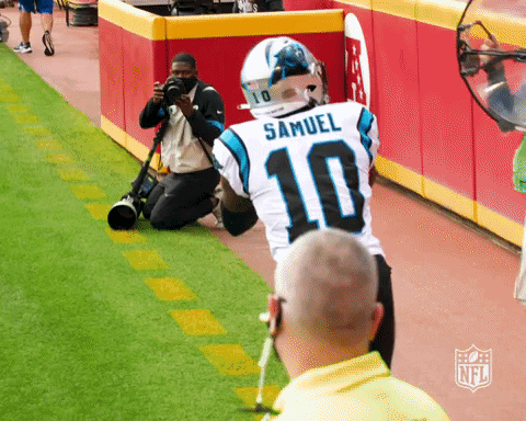 A Man Kneeling Down Taking A Picture Of A Football Player Wearing A Number 10 Jersey GIF