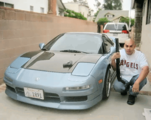 A Man Kneeling In Front Of A Car With A California License Plate That Reads 1891 GIF