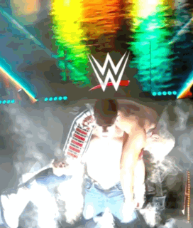 A Man Kneeling In Front Of A Wwe Logo GIF