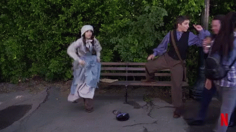 A Man Kneeling On A Bench Next To A Woman In A Blue Dress With A N On The Bottom GIF