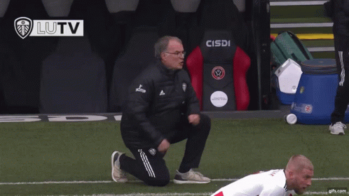A Man Kneeling On A Soccer Field In Front Of A Cisdi Chair GIF