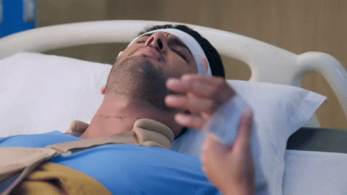 A Man Laying In A Hospital Bed With A Bandage On His Head GIF