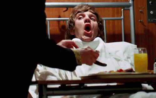 A Man Laying In A Hospital Bed With His Mouth Open And A Tray Of Food GIF